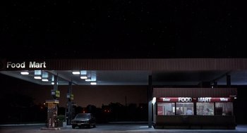 Movie still from “Reality Bites” (1994), directed by Ben Stiller – A car is parked at a gas station at night; Extreme Wide shot, Low angle