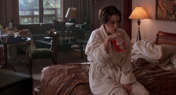 Movie still from “Reality Bites” (1994), directed by Ben Stiller – A woman sitting on a couch drinking a cup of coffee; Medium shot, High angle