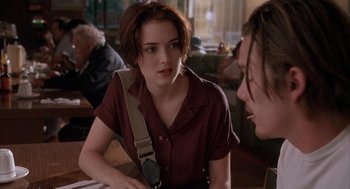 Movie still from “Reality Bites” (1994), directed by Ben Stiller – A woman sitting at a table talking to another person; Medium shot, Over the shoulder angle