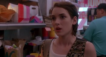 Movie still from “Reality Bites” (1994), directed by Ben Stiller – A young woman standing in front of a shelf; Close Up shot, Over the shoulder angle