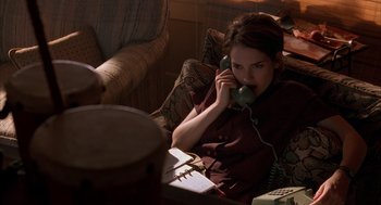Movie still from “Reality Bites” (1994), directed by Ben Stiller – A woman sitting on a couch talking on a phone; Medium shot, High angle
