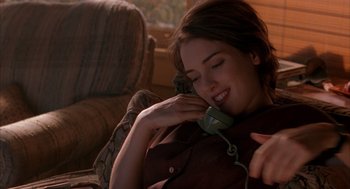 Movie still from “Reality Bites” (1994), directed by Ben Stiller – A woman is talking on a phone while laying on the couch; Close Up shot, High angle
