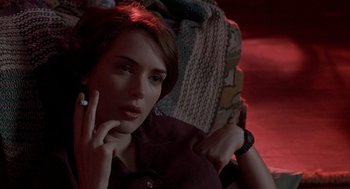 Movie still from “Reality Bites” (1994), directed by Ben Stiller – A woman sitting on a couch with her hand under her chin; Close Up shot, Over the shoulder angle