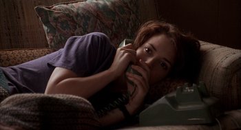 Movie still from “Reality Bites” (1994), directed by Ben Stiller – A woman laying on a couch holding a cell phone to her ear; Close Up shot, High angle