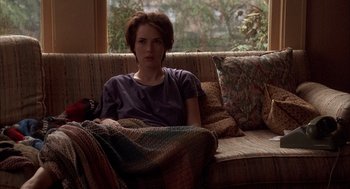 Movie still from “Reality Bites” (1994), directed by Ben Stiller – A woman sitting on a couch in a living room; Medium shot, High angle