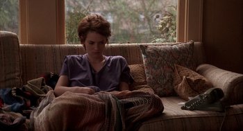 Movie still from “Reality Bites” (1994), directed by Ben Stiller – A woman sitting on a couch with a blanket; Medium shot, High angle