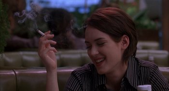 Movie still from “Reality Bites” (1994), directed by Ben Stiller – A woman smoking a cigarette while sitting in a booth; Close Up shot, Over the shoulder angle
