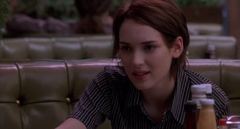 Movie still from “Reality Bites” (1994), directed by Ben Stiller – A woman sitting on a couch looking at the camera; Close Up shot, Over the shoulder angle