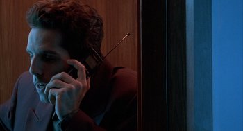 Movie still from “Reality Bites” (1994), directed by Ben Stiller – A man talking on a cell phone while sitting in a chair; Close Up shot, Low angle
