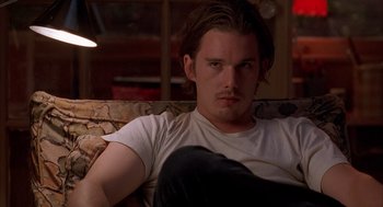 Movie still from “Reality Bites” (1994), directed by Ben Stiller – A man sitting on top of a couch in front of a window; Close Up shot, Low angle