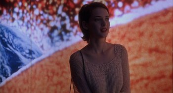 Movie still from “Reality Bites” (1994), directed by Ben Stiller – A woman standing in front of a large screen; Medium shot, Over the shoulder angle