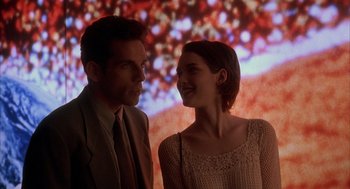 Movie still from “Reality Bites” (1994), directed by Ben Stiller – A man and a woman standing next to each other in front of a screen; Medium shot, Over the shoulder angle