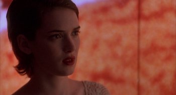 Movie still from “Reality Bites” (1994), directed by Ben Stiller – A woman's face in front of an orange background; Close Up shot, Over the shoulder angle