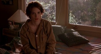 Movie still from “Reality Bites” (1994), directed by Ben Stiller – A woman sitting on a bed in a room; Medium shot, Over the shoulder angle