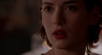 Movie still from “Reality Bites” (1994), directed by Ben Stiller – A woman's face in a dimly - lit room; Close Up shot, Over the shoulder angle
