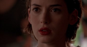 Movie still from “Reality Bites” (1994), directed by Ben Stiller – A woman's face in a dimly - lit room; Close Up shot, Over the shoulder angle