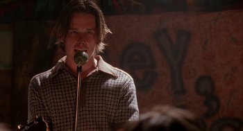 Movie still from “Reality Bites” (1994), directed by Ben Stiller – A man standing in front of a microphone on a stage; Close Up shot, Low angle