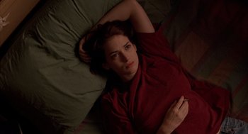 Movie still from “Reality Bites” (1994), directed by Ben Stiller – A woman laying in a bed wearing a red shirt; Medium shot, High angle