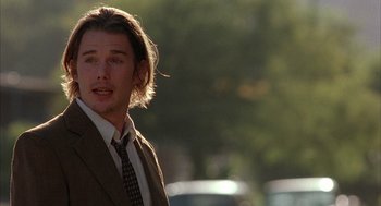 Movie still from “Reality Bites” (1994), directed by Ben Stiller – A man in a suit and tie standing in front of a street; Close Up shot, Over the shoulder angle