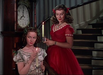 Movie still from “Reap the Wild Wind” (1942), directed by Cecil B. DeMille – Two young women holding lit candles in front of a clock; Medium shot, Low angle