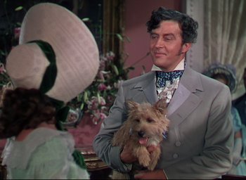 Movie still from “Reap the Wild Wind” (1942), directed by Cecil B. DeMille – A man in a suit holding a small dog; Medium shot, Over the shoulder angle
