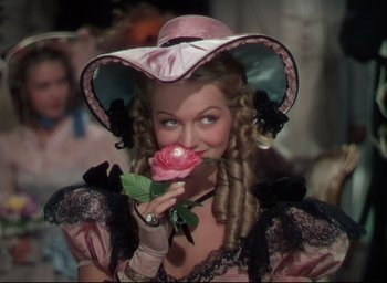 Movie still from “Reap the Wild Wind” (1942), directed by Cecil B. DeMille – A woman in a pink hat holding a pink rose; Close Up shot, Over the shoulder angle