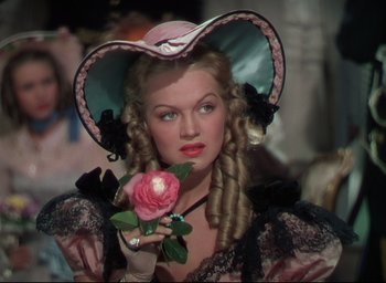 Movie still from “Reap the Wild Wind” (1942), directed by Cecil B. DeMille – A woman in a hat holding a pink rose; Close Up shot, Over the shoulder angle