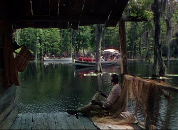 Movie still from “Reap the Wild Wind” (1942), directed by Cecil B. DeMille – A man sitting on a dock in the water; Extreme Wide shot, Over the shoulder angle