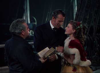 Movie still from “Reap the Wild Wind” (1942), directed by Cecil B. DeMille – A man and a woman are holding a book and talking to another man; Medium shot, Over the shoulder angle