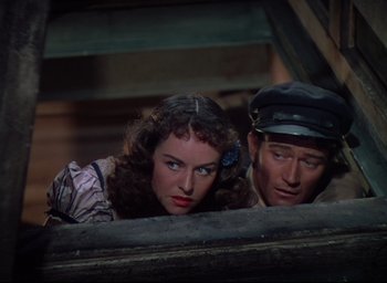Movie still from “Reap the Wild Wind” (1942), directed by Cecil B. DeMille – A man and a woman looking over a fence; Medium shot, High angle