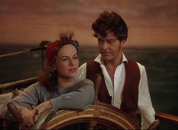Movie still from “Reap the Wild Wind” (1942), directed by Cecil B. DeMille – A man and a woman sitting at the steering wheel of a boat; Medium shot, High angle