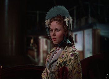 Movie still from “Reap the Wild Wind” (1942), directed by Cecil B. DeMille – A woman in a floral print dress and a hat; Medium shot, Over the shoulder angle