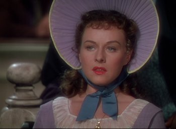 Movie still from “Reap the Wild Wind” (1942), directed by Cecil B. DeMille – A woman in a purple hat and a pink dress; Close Up shot, Over the shoulder angle
