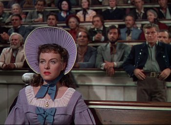 Movie still from “Reap the Wild Wind” (1942), directed by Cecil B. DeMille – A woman wearing a hat in front of an audience; Medium shot, Over the shoulder angle