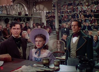 Movie still from “Reap the Wild Wind” (1942), directed by Cecil B. DeMille – A group of people sitting around a table; Medium shot, Over the shoulder angle