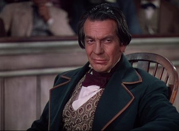 Movie still from “Reap the Wild Wind” (1942), directed by Cecil B. DeMille – A person sitting in a chair wearing a suit; Close Up shot, High angle