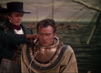 Movie still from “Reap the Wild Wind” (1942), directed by Cecil B. DeMille – A man is fixing another man's hair while he is wearing a suit and tie; Medium shot, Over the shoulder angle