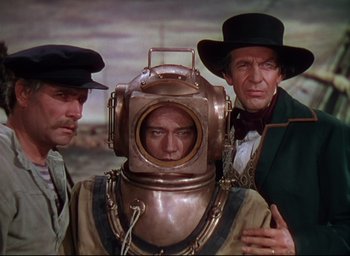 Movie still from “Reap the Wild Wind” (1942), directed by Cecil B. DeMille – A man in a diving suit with two other men in hats; Medium shot, High angle