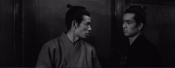 Movie still from “Red Beard” (1965), directed by Akira Kurosawa – A black and white photo of a man in a kimono; Close Up shot, Over the shoulder angle