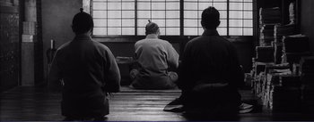 Movie still from “Red Beard” (1965), directed by Akira Kurosawa – A group of people sitting on the ground in front of a window; Wide shot, Low angle