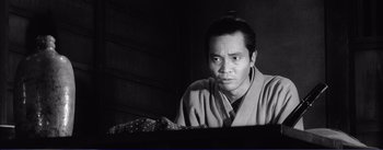 Movie still from “Red Beard” (1965), directed by Akira Kurosawa – A black and white photo of a man in a robe; Close Up shot, Low angle