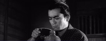 Movie still from “Red Beard” (1965), directed by Akira Kurosawa – A black and white photo of a man drinking from a jar; Close Up shot, Low angle