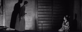 Movie still from “Red Beard” (1965), directed by Akira Kurosawa – A man standing in front of a candle in a dark room; Wide shot, Low angle