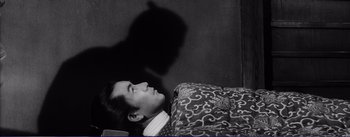 Movie still from “Red Beard” (1965), directed by Akira Kurosawa – A man laying in bed with his shadow on the wall; Medium shot, High angle