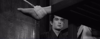 Movie still from “Red Beard” (1965), directed by Akira Kurosawa – A black - and - white photo of a man with a bandaged arm; Close Up shot, Low angle