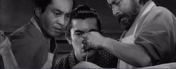 Movie still from “Red Beard” (1965), directed by Akira Kurosawa – A man with a mustache is holding a straw; Close Up shot, High angle