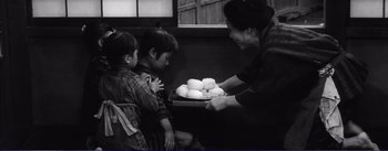 Movie still from “Red Beard” (1965), directed by Akira Kurosawa – A woman holding a tray of food with two children; Medium shot, Low angle