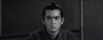 Movie still from “Red Beard” (1965), directed by Akira Kurosawa – A black and white photo of a man with a long black hair; Close Up shot, High angle