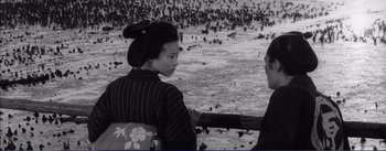 Movie still from “Red Beard” (1965), directed by Akira Kurosawa – A woman sitting next to a man on a pier; Medium shot, High angle