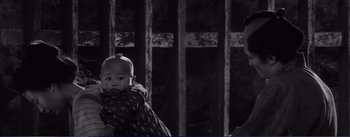 Movie still from “Red Beard” (1965), directed by Akira Kurosawa – A baby is wrapped in a blanket in front of a fence; Close Up shot, High angle